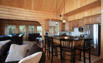 a spacious living room with wooden walls and ceiling , a kitchen area , and a dining table at Fiddler Lake Resort