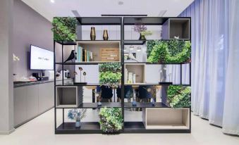 The room is decorated in an oriental style, with shelves and plants on the wall in front at Home Inn (Shanghai North Bund Dalian Road Subway Station)