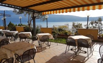 a restaurant patio with tables and chairs under a yellow awning , overlooking a body of water at All Inclusive Hotel Piccolo Paradiso