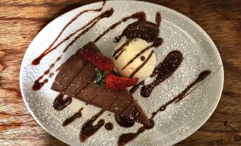 a white plate with a slice of chocolate cake and a scoop of ice cream on top at The Sun Inn