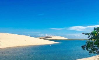 a vast , sandy desert landscape with a clear blue lake surrounded by white sand dunes at Star Hotel