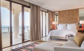 a luxurious bedroom with a king - sized bed , a couch , and a large window overlooking the ocean at Four Seasons Hotel Tunis