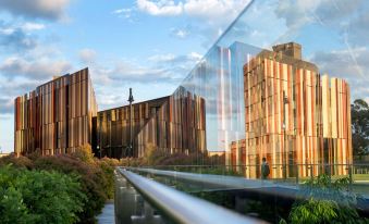 a modern building with a glass facade and a person standing on the edge of a bridge at Meriton Suites North Ryde