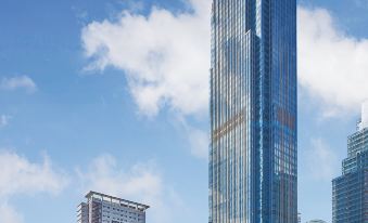 a tall , modern skyscraper stands against a backdrop of other skyscrapers and clouds in the sky at Grand Hyatt Manila