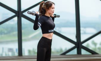 A woman in the gym stretches her arms out while another person stands behind her at Global Hotel