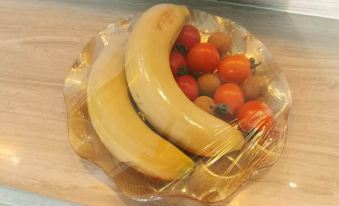 a plate of bananas and tomatoes wrapped in plastic , placed on a table in a restaurant at Open Hotel
