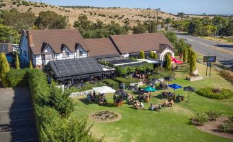 aerial view of a large house with a green lawn and various outdoor activities , such as picnics , playing golf , and sunbathing at Mick O'Sheas