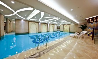 an indoor swimming pool with a blue and white color scheme , surrounded by chairs and tables at Central Hotel