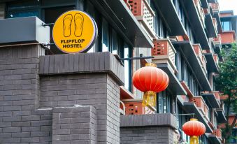 A sign hangs from the top side of an Asian-style building in front at Poshpacker Flipflop Youth Hostel (Taikoo Li Chunxi Road Metro Station)