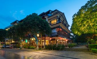 a large building with multiple floors and balconies , surrounded by trees and lit up at night at Riverview Hotel
