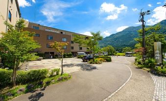 a large , well - maintained parking lot with several cars parked in it , and a building with a car wash at Yufuin Hotel Shuhokan