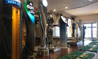 a bar with a variety of beer taps , including heineken , boots , and guinness , along with a green mat on the counter at The Anchorage Hotel