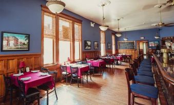 a large dining room with wooden tables and chairs , a television , and framed pictures on the wall at The Hotel Belvidere