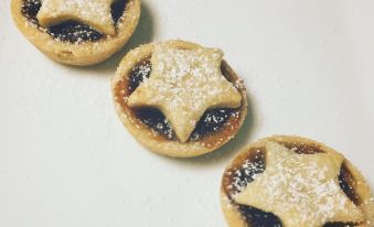 three small tarts with star - shaped fillings are arranged in a line on a white surface at The Red Lion Inn