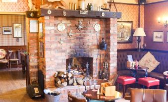 a cozy living room with a fireplace and various decorations , including deer heads on the mantle at The Red Lion