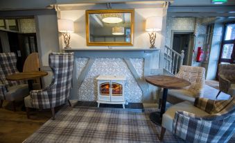 a cozy living room with a fireplace , a fireplace heater , and a dining table at The Stair Arms Hotel