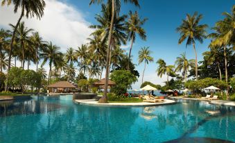 a large resort with a pool surrounded by palm trees and lounge chairs on the beach at Holiday Resort Lombok