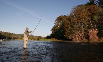 a man is fishing in a river , casting a fishing rod and preparing to cast it at Red Lion Inn
