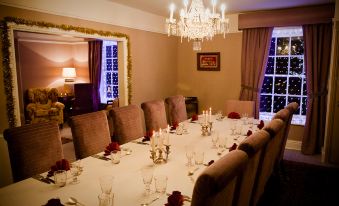 a formal dining room with a long table covered in white tablecloths and adorned with wine glasses and candles at The Carden Arms