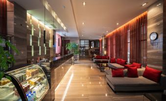 a modern hotel lobby with red couches , wooden floors , and a variety of seating options at Good Hotel (Beijing East Road Gaoxin Avenue Subway Station)
