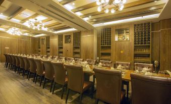 a dining room with a long wooden table surrounded by chairs , and a chandelier hanging above at Westlake Hotel & Resort Vinh Phuc