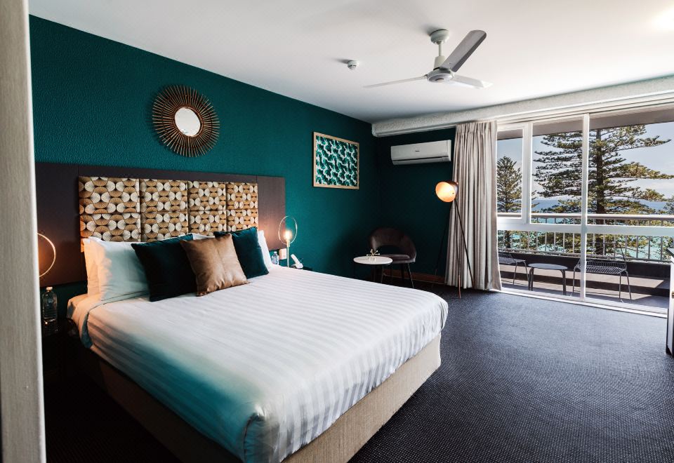 a modern bedroom with a large bed , white linens , and a window offering a view of the outdoors at Greenmount Beach House