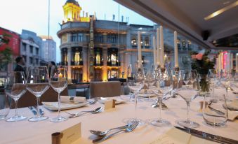 A table is set for dinner at an outdoor restaurant with a view of a filming location and other scenery at Radisson Collection Hyland Shanghai