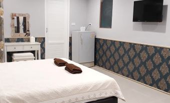 a cozy bedroom with a white bed , a tv mounted on the wall , and a bathroom next to it at Tipviman Resort