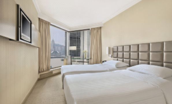 The bedroom features double beds and large windows that offer a view of the downtown area at The Kowloon Hotel