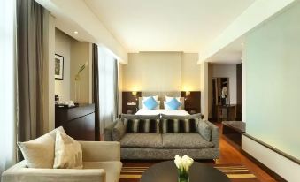 a modern hotel room with a bed , couch , and dining table , as well as a living area with a couch and a television at Novotel Jakarta Mangga Dua Square