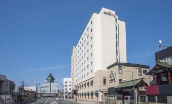 a city street with a tall building on the left side and a smaller building on the right side at Hotel JAL City Aomori