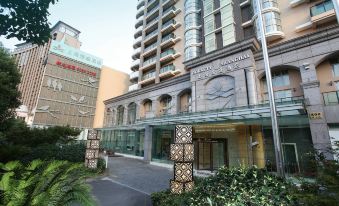 The entrance to a hotel in an urban setting is characterized by large buildings and stone walkways at Dorsett Shanghai