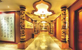 a long , elegant hallway with golden columns and a chandelier hanging from the ceiling , leading to a room filled with paintings at Silver Sea Hotel