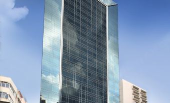 A tall skyscraper is situated on top of a large building with an office tower in the middle at iclub To Kwa Wan Hotel