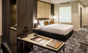 a modern hotel room with a large bed , wooden walls , and a desk area with papers and a phone at DoubleTree by Hilton Wellington
