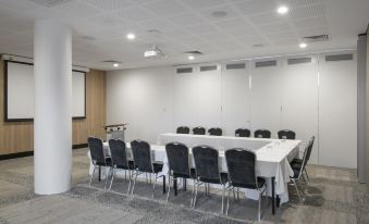 a large conference room with multiple rows of chairs arranged in a semicircle , providing seating for a group of people at Metro Hotel Perth