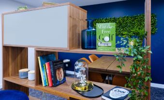 "a modern office space with a wooden desk , green plants , and books , as well as a blue wall with the text "" mistakes free cop" at Mantra Albury Hotel