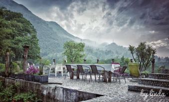 There is an outdoor dining area with a patio that offers a scenic view of the mountains, furnished with tables and chairs at Little Forest Guesthouse