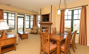 a spacious living room with a dining table and chairs , a fireplace , and large windows at The Appalachian at Mountain Creek