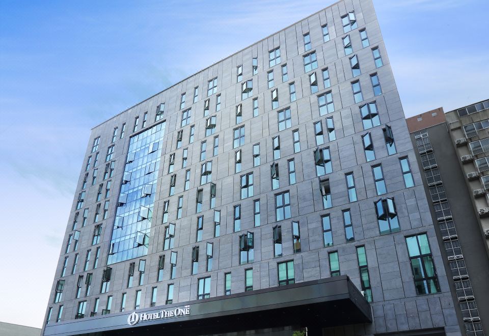 a modern building with many windows and a clear blue sky in the background , under a clear blue sky at Hotel the One