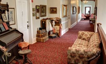 a hallway with a red carpet , carpeted floor , and various pieces of furniture such as chairs , a couch , and a table at Grand Victorian Inn
