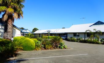 a white building with a car parked in front and several other cars behind it at Torquay Tropicana Motel