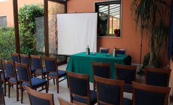 a conference room with chairs arranged in rows and a projector screen set up on the wall at Panorama Hotel