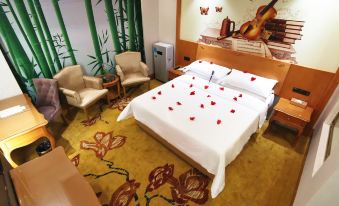a hotel room with a large bed , red rose petals , and a mural of bamboo on the wall at Vienna Hotels