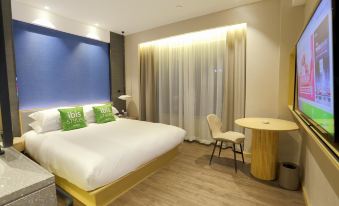 a hotel room with a king - sized bed , a desk , a chair , and a tv . the room is clean and well - organized at Ibis Styles Hotel