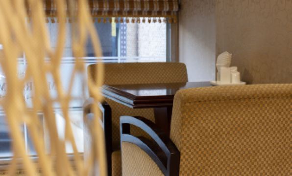 a dining area with several chairs and tables , some of which are placed near a window at Symphony Hotel