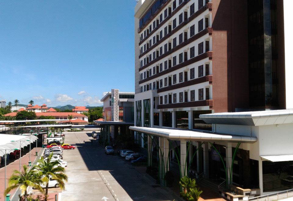 a tall building with a red and white facade is next to a parking lot at HIG Hotel