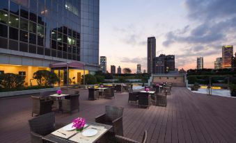 a rooftop restaurant with tables and chairs that offers a view of an outdoor seating area in front at Jin Jiang Tower