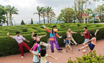 In the background of a group photo, children can be seen playing at an amusement park on either side at Hong Kong Disneyland Hotel