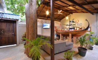 a room with a couch , wooden ceiling beams , and a boat on the wall , surrounded by potted plants at Beach Villa Ukulhas